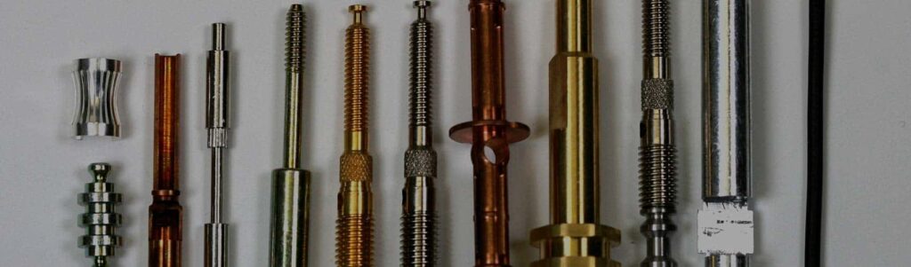 Ruuvikoneella valmistettuja eri osia on rivissä tasaisella valkoisella pinnalla